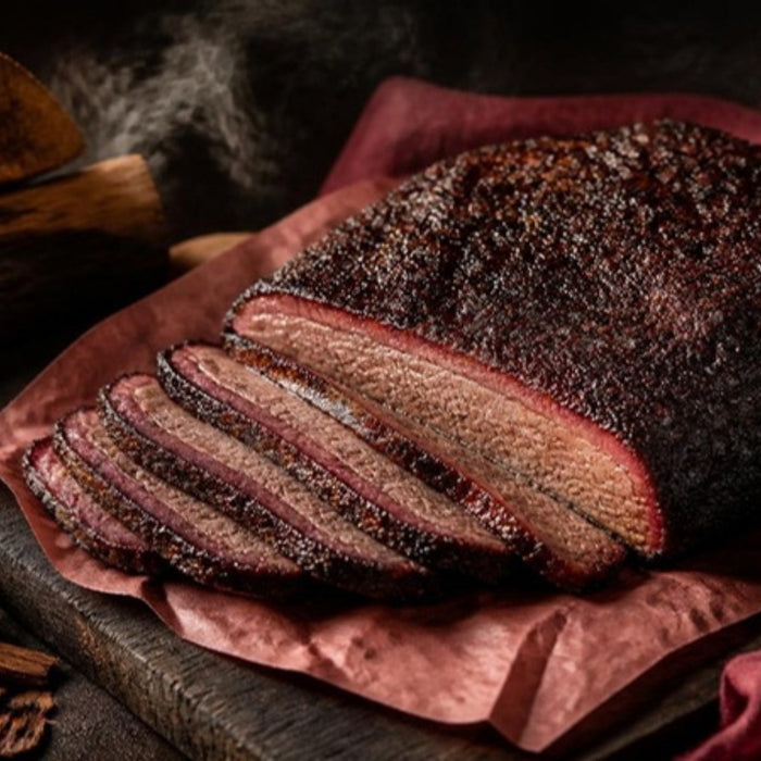 Smoked brisket on butcher paper with oak and cherry wood chunks
