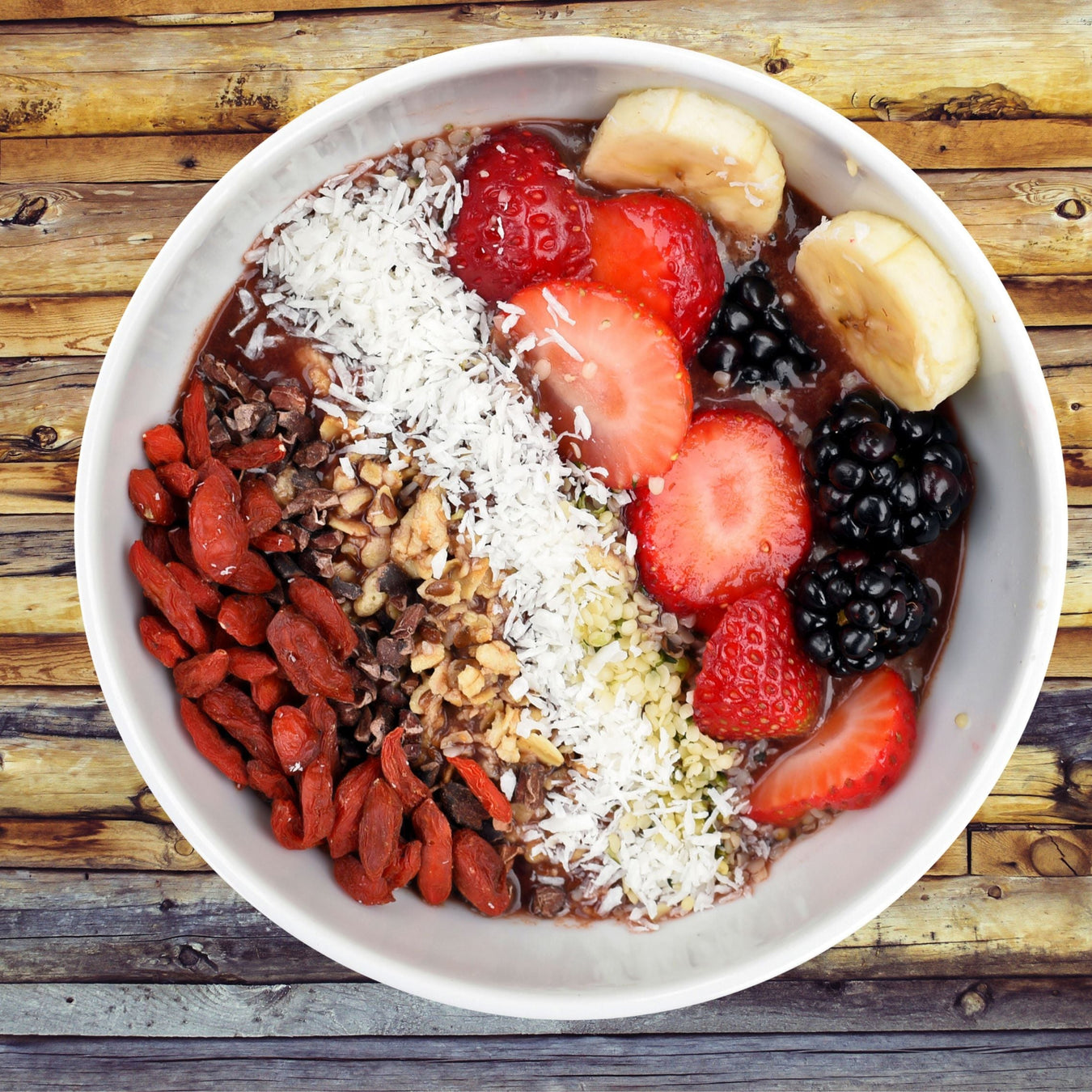 Açaí bowl topped with goji berries, cacao nibs, granola, coconut, hemp seeds, strawberries, blackberries and banana